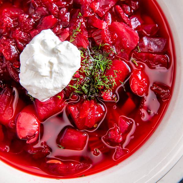 Borscht in a white bowl with a dollop of sour cream on top