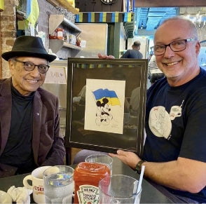 Veselka meeting original mickey mouse illustrator who gifted a framed illustration of mickey mouse holding a Ukrainian flag