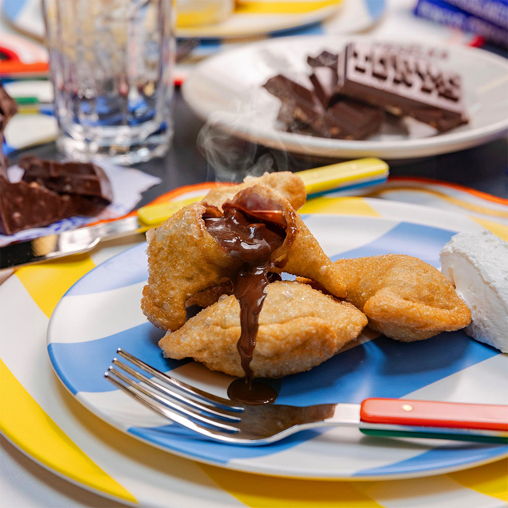 Chocolate gooey pierogi, fried on striped colorful plate. Tony's chocolate bar in the background.