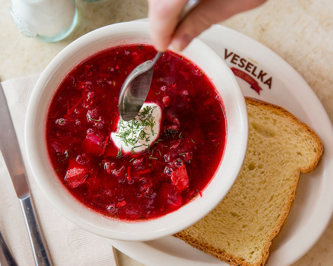 Borscht with bread and sour cream served on a veselka plate and bowl