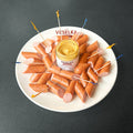 Pork Kabanos on a plate with spicy brown mustard in the middle and some colorful toothpicks 