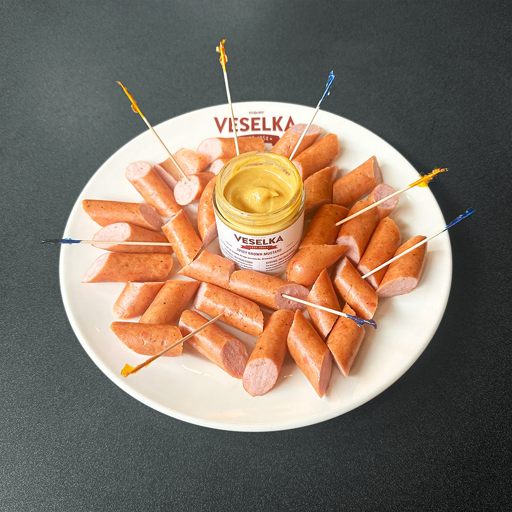 Pork Kabanos on a plate with spicy brown mustard in the middle and some colorful toothpicks 