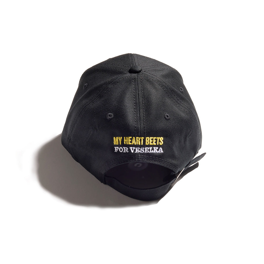 Black baseball cap with "My heart beets for Veselka" written on the back in yellow and white 